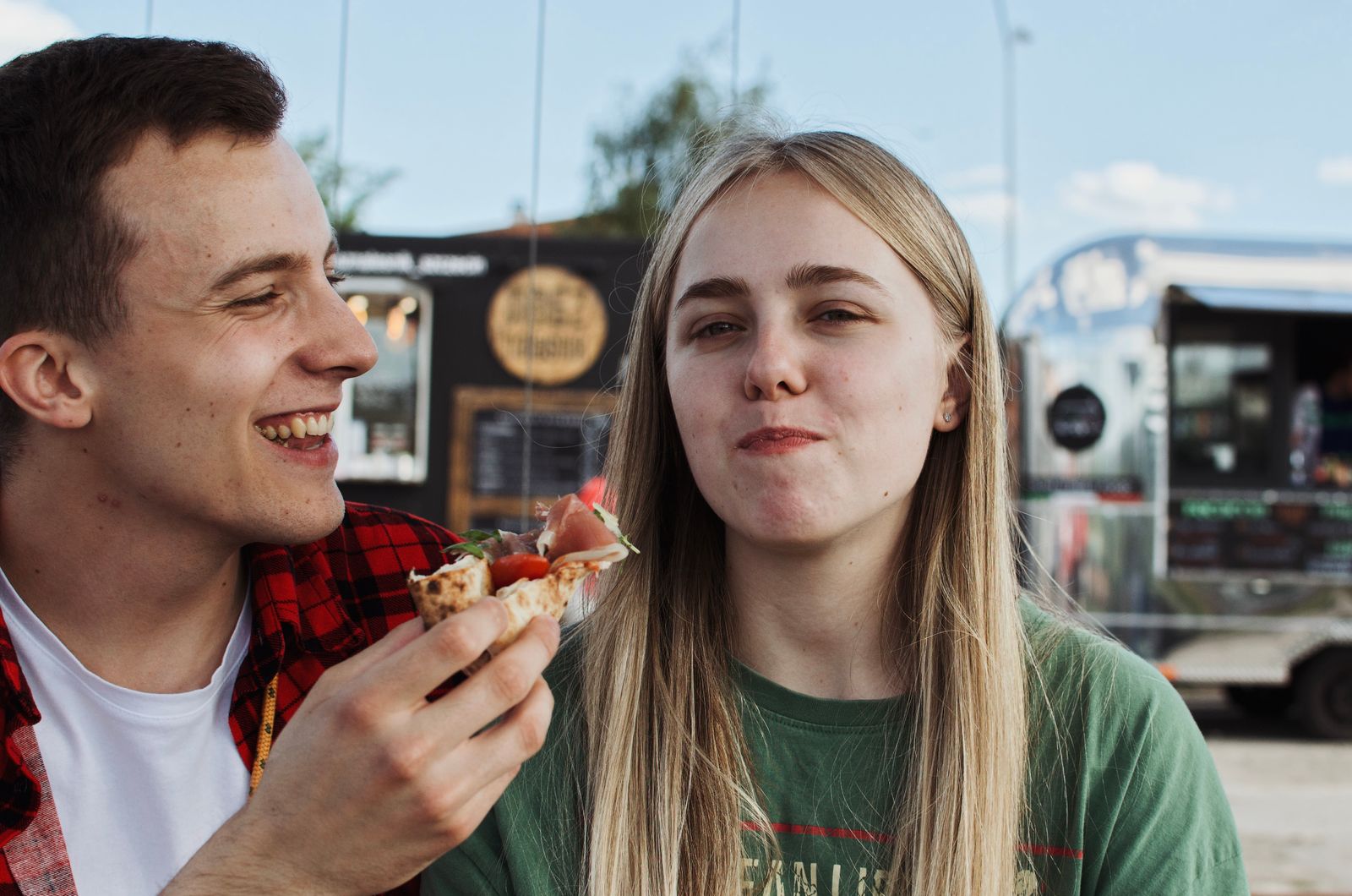 A couple eating street food in front of an Airstream catering trailer